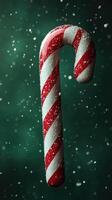 Red and white striped candy cane suspended in snowy atmosphere during festive winter season photo
