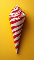 Colorful dessert cone with red and white swirls topped with sprinkles against a yellow background photo