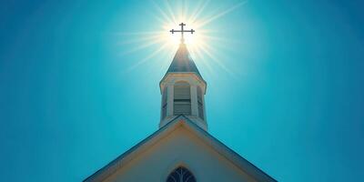 Bright sunlight shines behind church steeple, creating a halo effect at noon on a clear day photo