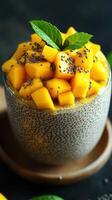 Delicious mango chia pudding topped with fresh mango and mint served in a glass photo