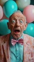 Surprised elderly man with blue eyes and bowtie in front of colorful balloons during a celebration photo