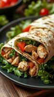 Fresh chicken wrap with vegetables served on a black plate at a casual dining setting photo