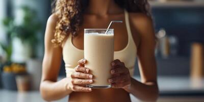 Woman holding a refreshing smoothie in a bright kitchen while enjoying a healthy lifestyle photo