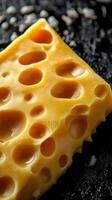 High-quality close-up of Swiss cheese on dark textured surface with unique holes and creamy texture photo