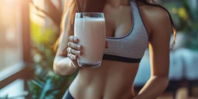 Woman enjoying a healthy smoothie in athletic wear with sunlight streaming through a window photo