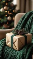 Beautifully wrapped gift sits on cozy green blanket near decorated Christmas tree with soft lights in a warm indoor setting photo