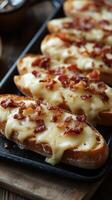 Deliciously toasted bread topped with melted cheese and crispy bacon served on a wooden platter photo