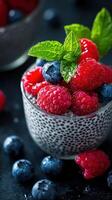 Fresh berries served in a textured glass with mint leaves on a dark surface photo