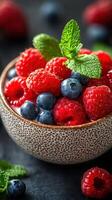 Fresh strawberries and blueberries in a textured bowl garnished with mint leaves on a dark background photo