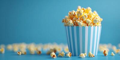 Freshly popped popcorn fills a striped container against a bright blue background creating a playful and inviting atmosphere photo