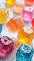 Colorful gummy candies in various shapes and flavors scattered on a white surface with sparkling sugar crystals photo