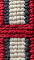 Textured close-up of woven textile featuring bold red, black, and cream patterns in intricate design photo