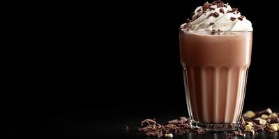Delicious chocolate drink topped with whipped cream and chocolate shavings in a clear glass on a dark background photo