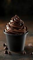 Delicious chocolate swirl dessert served in a black cup on a rustic surface with chocolate chips scattered around photo