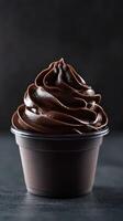 Rich chocolate soft serve dessert in a cup on a dark background with smooth swirls and glossy finish photo