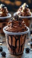 Delicious chocolate dessert topped with blackberries in a clear cup on a textured surface photo