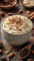 Creamy dessert topped with crushed nuts in a rustic bowl surrounded by spices and other ingredients photo