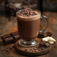 Warm chocolate drink topped with shavings served with dark chocolate pieces on rustic wooden surface photo
