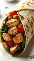 Delicious chicken wrap filled with fresh spinach, tomatoes, and grilled chicken pieces photo