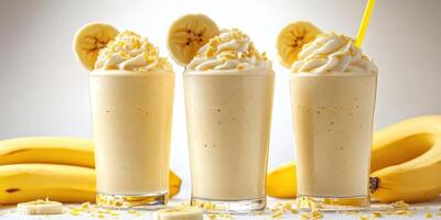 Delicious banana milkshakes served in clear glasses with banana slices and whipped cream on top photo