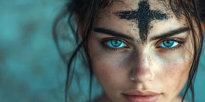 Young woman with striking blue eyes and ash mark on forehead participates in ritual ceremony during Lent season photo