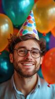 Man smiles with joy at a colorful birthday celebration surrounded by balloons photo