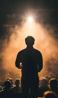 Silhouette of a speaker addressing an audience in a dimly lit, smoky environment at the event photo