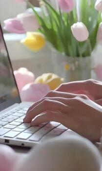 Typing on a laptop with flowers and marshmallow adding a touch of spring to the work area photo