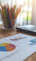 Analyzing Business Performance with Charts, Graph, Keyboard and Color Pencils on Wooden Table photo