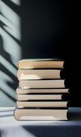 A stack of timeless books bathed in sunlight with aesthetic shadow play on the backdrop photo