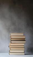 An arranged stack of books in an aesthetic composition against a solid gray backdrop photo