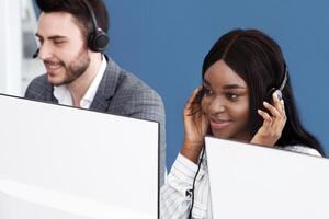 Team of young hotline consultants working with computers at call centre photo