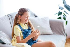 Amazing Application. Casual glad teenage kid with ponytails using smart phone, typing and sending message photo