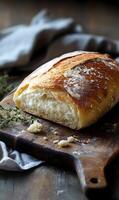 Artisanal bread loaf resting upon a vintage wooden board with a rustic fabric backdrop. photo