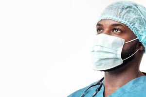 Ready to fight with flu. Young African American man surgeon in mask and hair net looking at copy space over white background photo