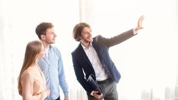 Millennial couple with cheerful real estate agent visiting house for sale photo