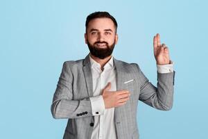 Portrait of millennial businessman taking oath against blue background photo
