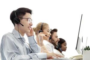 Diverse team of call centre operators working with computers at modern open space office. Group of helpdesk consultants managing customer's requests through VoIP telephony photo
