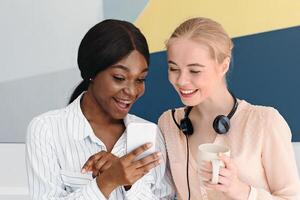 Female customer support operators with mobile phone and their coworkers at call centre, space for text photo