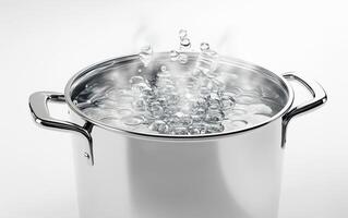 Boiling water in a stainless steel pot on a clean kitchen surface photo
