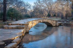 Rustic Stone Bridge Over Tranquil Stream in Serene Winter Landscape photo