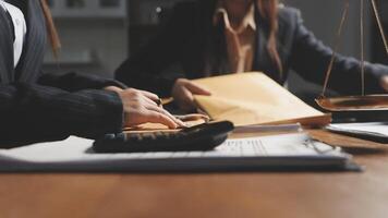 Two business people sitting at a desk with a calculator and papers video