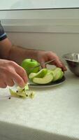 Man is Cutting Green Apples with Knife on a Plate. Vertical video
