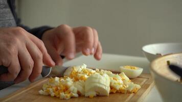 Man is Dicing and Cutting Boiled Eggs with Knife on Cutting Board. Close-Up Shot video