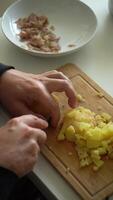 Man is Cutting and Dicing Boiled Potato with Knife on a Cutting Board. Vertical . Close-Up Shot video