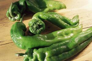 A bunch of green peppers sitting on a table photo
