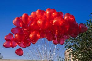 many red balloons in shape of a heart on the background of blue sky photo