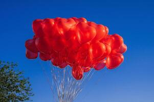 bunch of red balloons in shape of a heart on background of blue sky photo