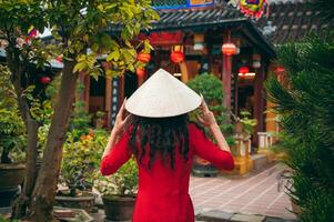 Back of a female tourist traveler in a Vietnamese cone hat Non La at Buddhist temple in Hoi An in Vietnam in Asia photo