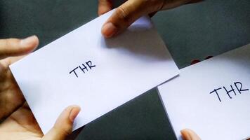 Photo concept of someone giving salary allowances in an envelope marked THR. This THR is a salary allowance that is usually given to employees before the Eid al-Fitr holiday in Indonesia